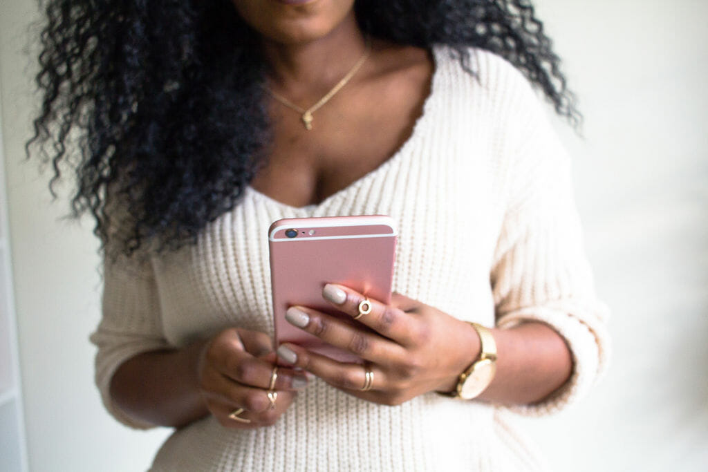 Woman in a white sweater holding a pink phone