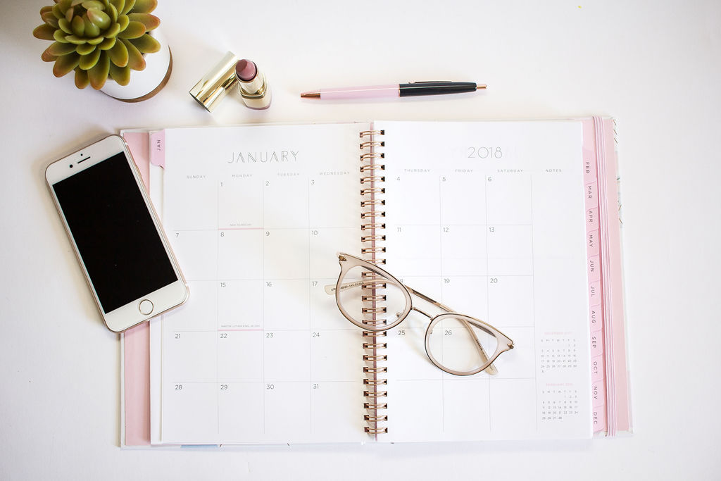Pink planner with a phone and glasses