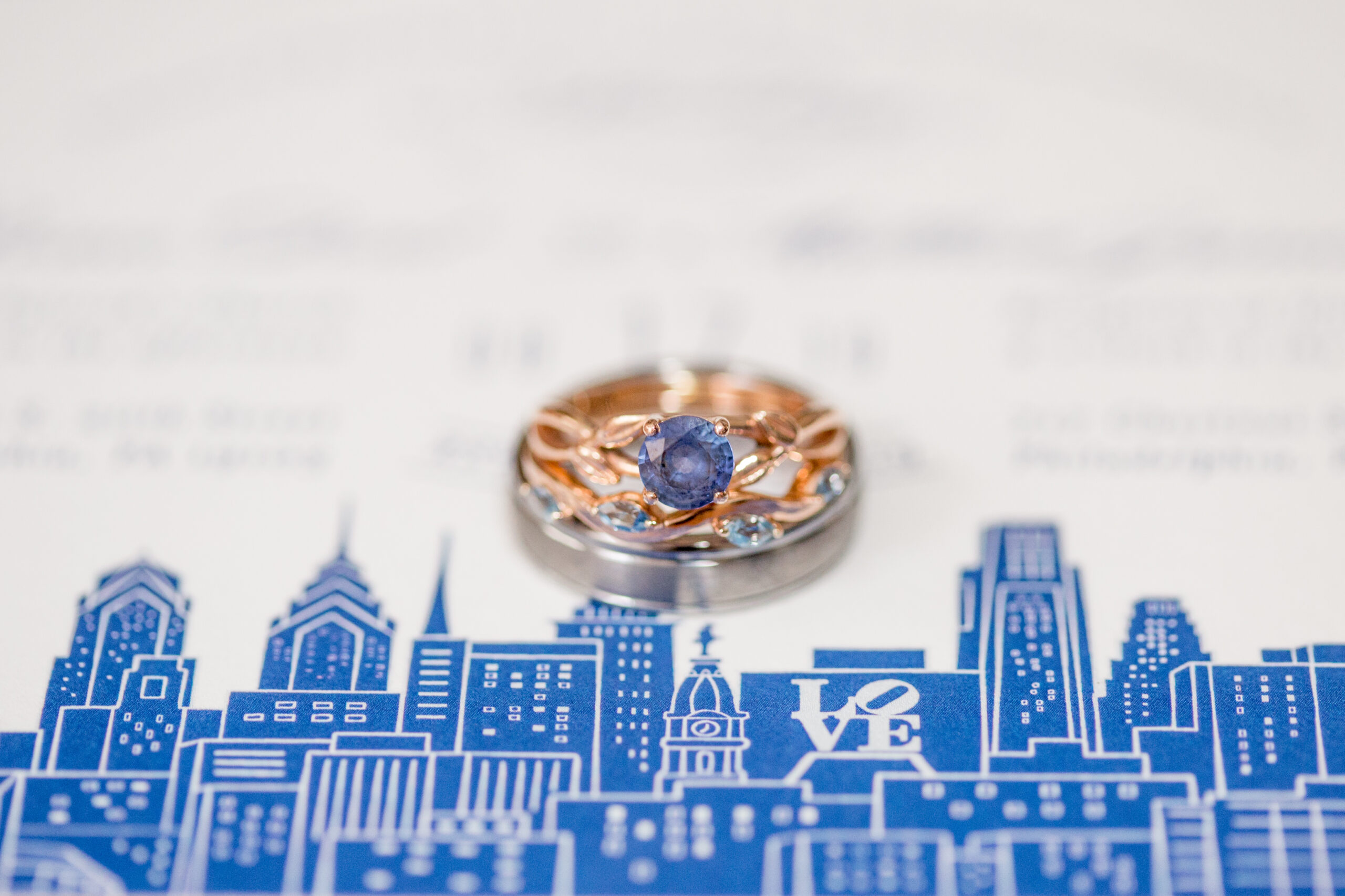 Stack of wedding rings on top of a blue wedding invitation
